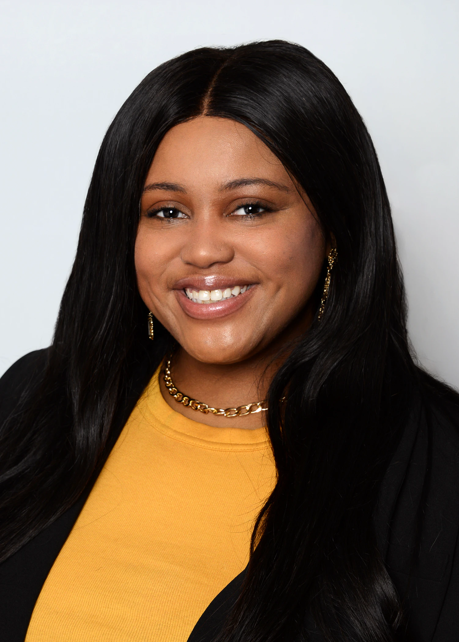 Portrait of a person smiling against a plain light background.