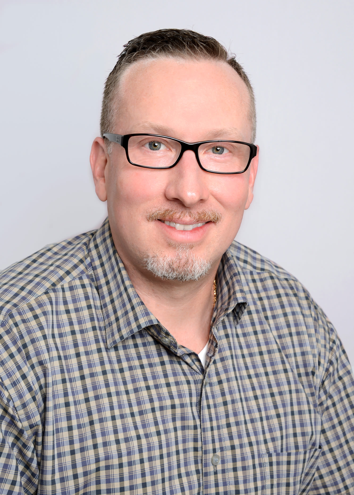 Man with glasses in plaid shirt headshot