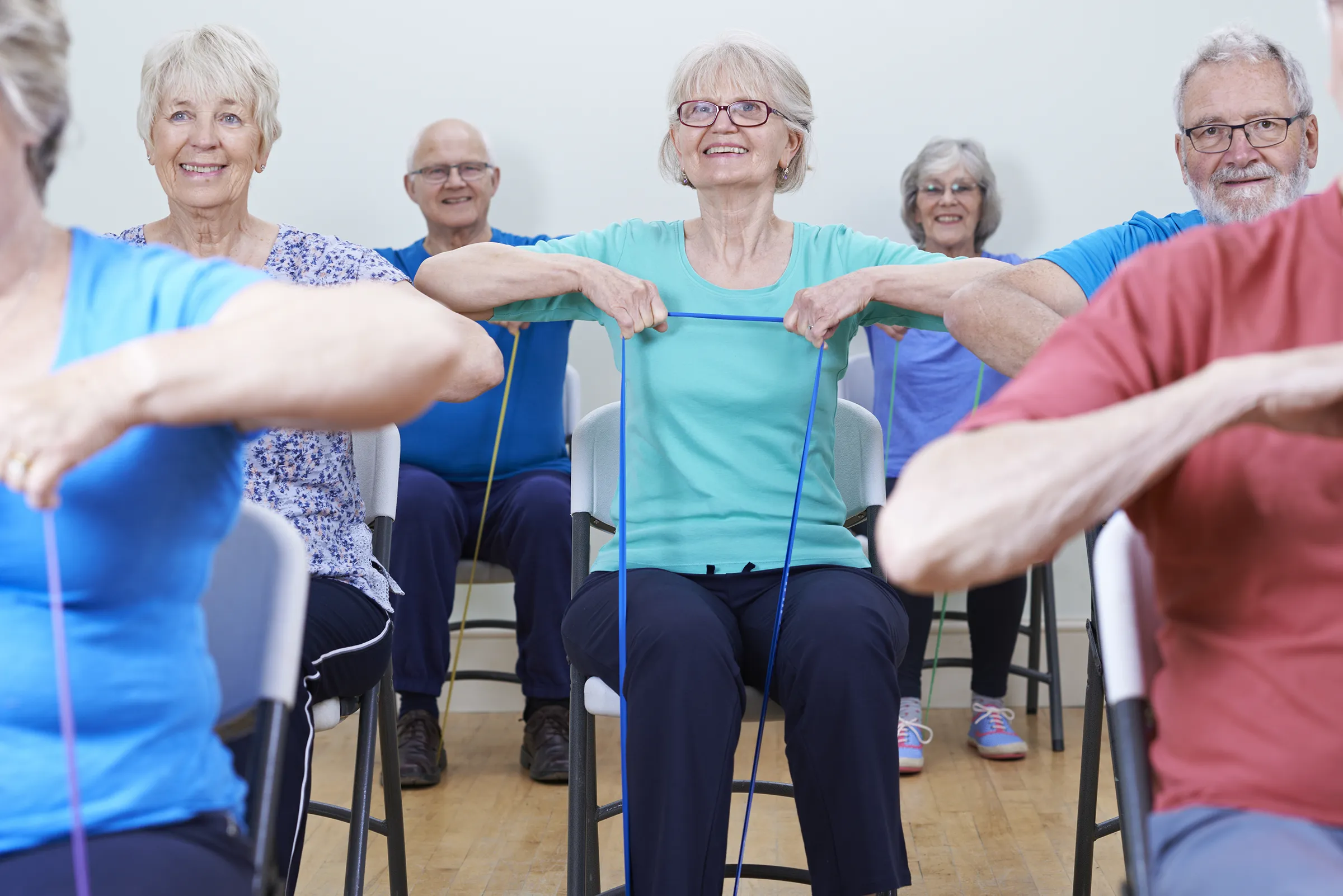 Seniors seated in chairs participating in a group exercise class with resistance bands at The Birches at New Hope community.
